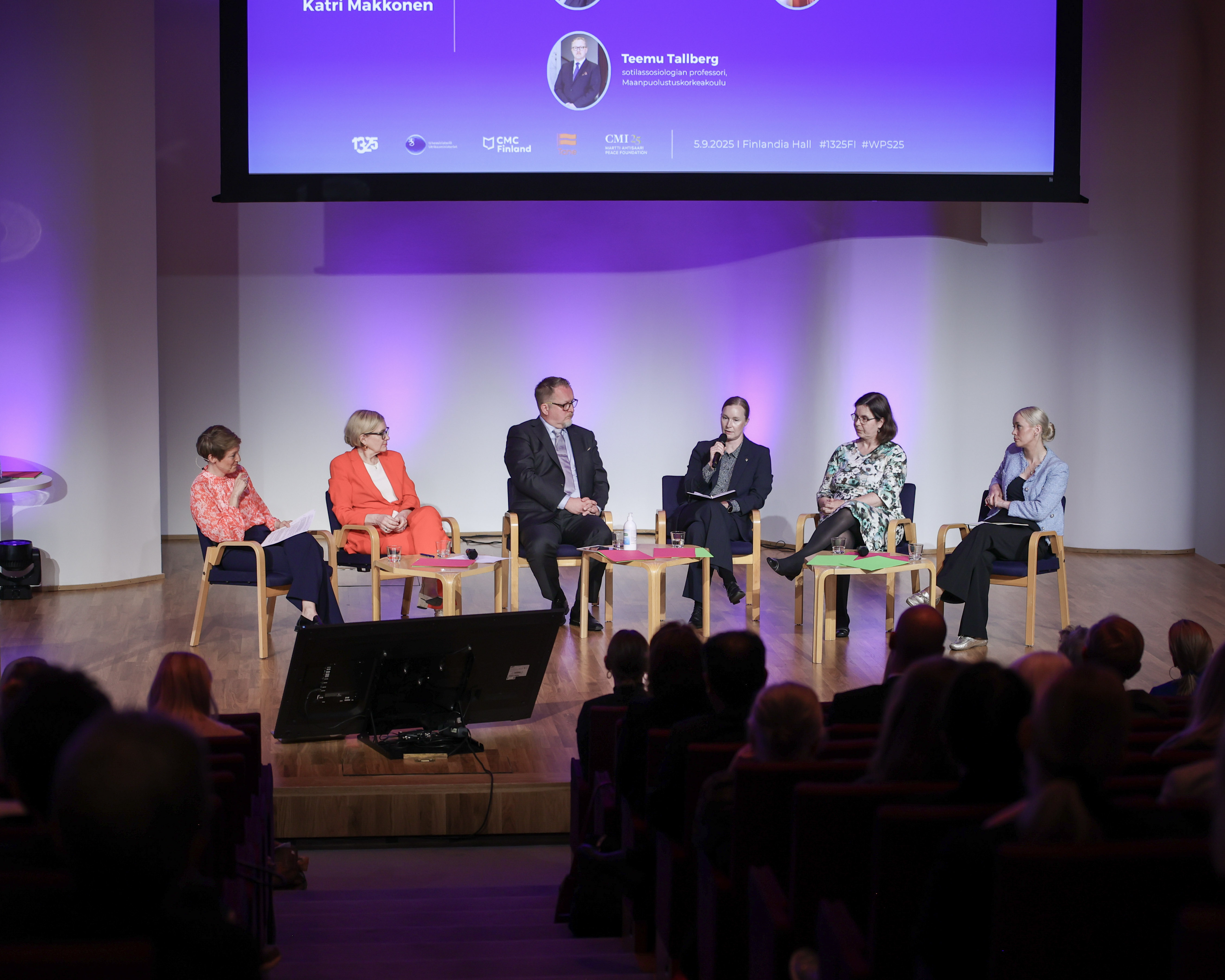Panelistit lavalla istumassa.